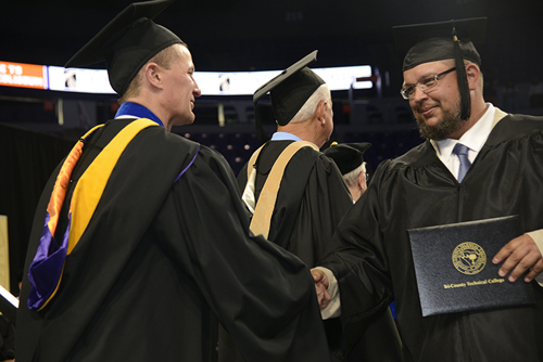 Dr. Galen DeHay shaking hands with a graduate